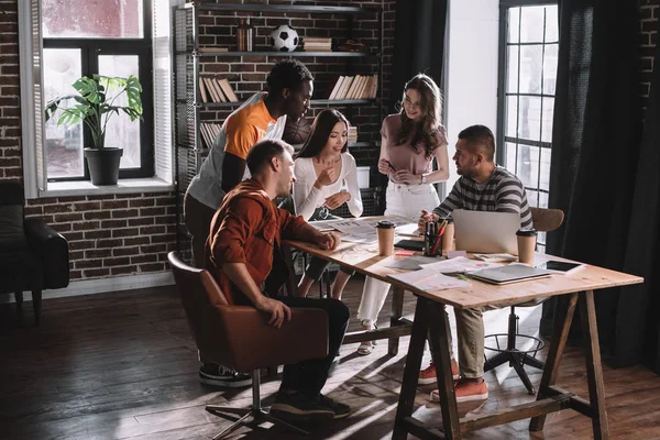 Jeunes gens d'affaires multiculturels positifs remue-méninges près du bureau au bureau — Photo de stock