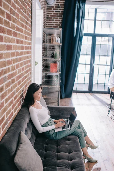 Visão de alto ângulo de jovem empresária usando laptop enquanto se senta no sofá — Fotografia de Stock