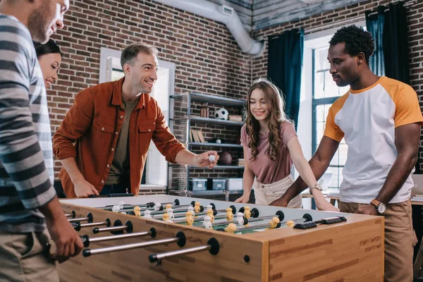 Empresários multiculturais alegres jogando futebol de mesa no escritório — Fotografia de Stock