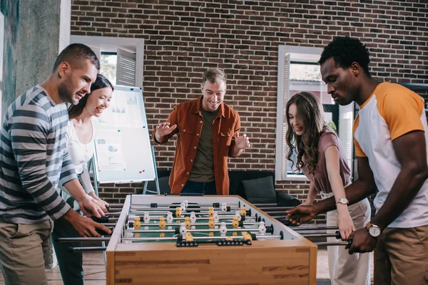 Empresários multiculturais alegres jogando futebol de mesa no escritório — Fotografia de Stock