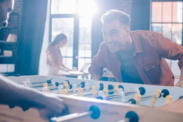 Cheerful multicultural businesspeople playing table soccer in office — Stock Photo