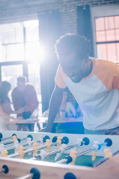 Emocionado hombre de negocios afroamericano jugando fútbol de mesa en la oficina - foto de stock