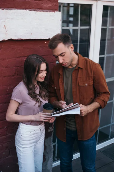 Thoughtful businessman showing documents to smiling colleague holding coffee to go — Stock Photo