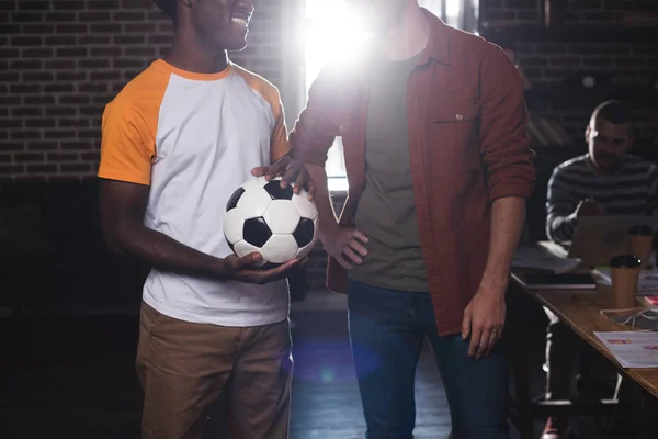 Cropped view of african american businessman holding soccer ball near colleague standing with hand on hip — Stock Photo