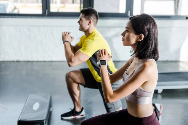 Side view of handsome sportsman and sportswoman doing lunges in sports center — Stock Photo