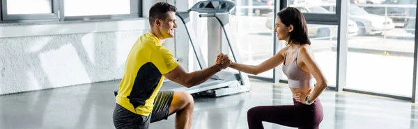 Panoramic shot of sportsman and sportswoman doing lunges together in sports center — Stock Photo