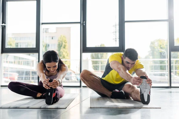 Спортсмен і спортсменка, що тягнеться на фітнес-матеріали в спортивному центрі — стокове фото