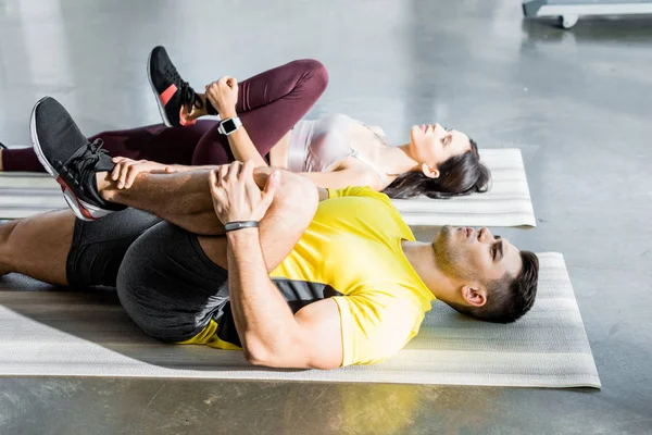 Deportista y deportista estirándose en colchonetas de fitness en el centro deportivo - foto de stock