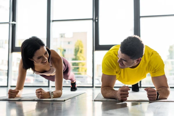 Sportivo sorridente e sportiva che fa tavola su tappetini fitness nel centro sportivo — Foto stock