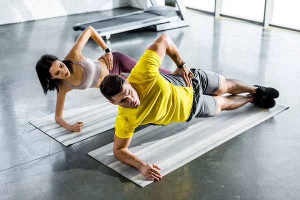 Desportista e desportista fazendo prancha em tapetes de fitness no centro de esportes — Fotografia de Stock