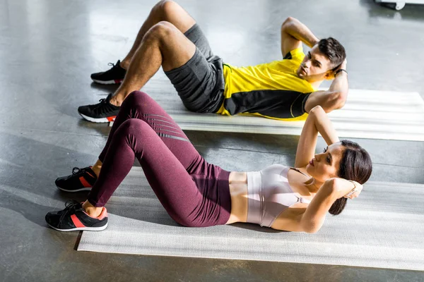 Desportista e desportista fazendo crunches em tapetes de fitness no centro desportivo — Fotografia de Stock