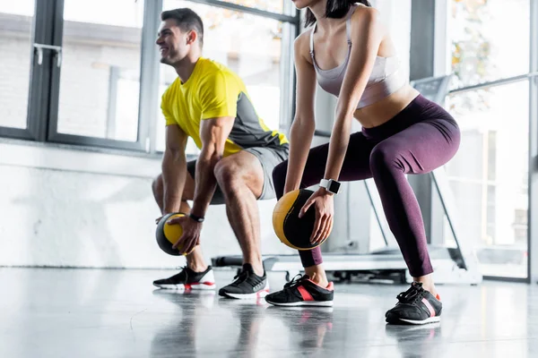 Спортсмен и спортсменка делают приседания с мячами в спорткомплексе — Stock Photo