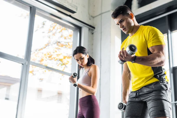 Desportista e desportista trabalhando com halteres no centro desportivo — Fotografia de Stock