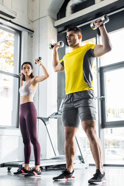 Sportsman and sportswoman working out with dumbbells in sports center — Stock Photo