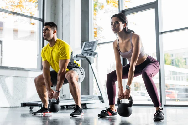 Sportsman and sportswoman doing squat with weights in sports center — Stock Photo