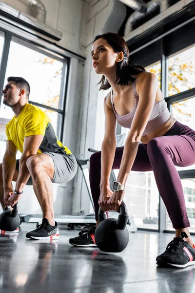 Deportista y deportista haciendo sentadilla con pesas en centro deportivo - foto de stock