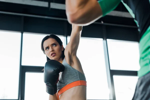 Sportlerin in Boxhandschuhen trainiert mit Sportler im Sportzentrum — Stockfoto