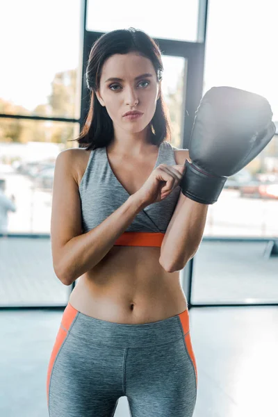 Sportswoman wearing boxing glove and looking at camera in sports center — Stock Photo