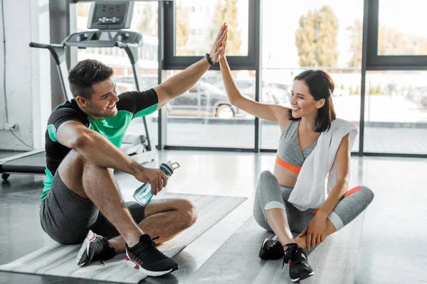 Sportsman and sportswoman sitting and giving high five in sports center — Stock Photo