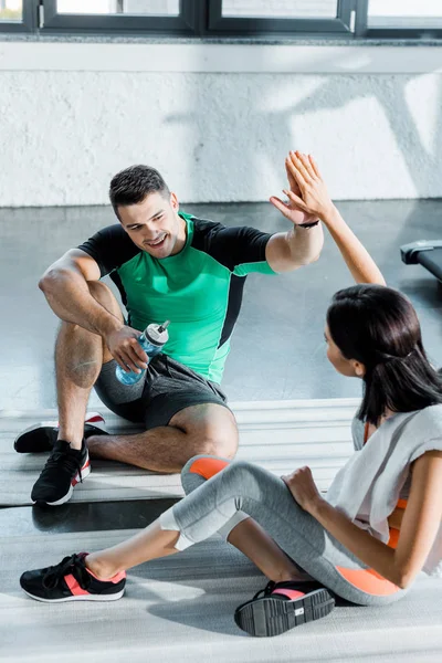 Sportsman and sportswoman sitting and giving high five in sports center — Stock Photo