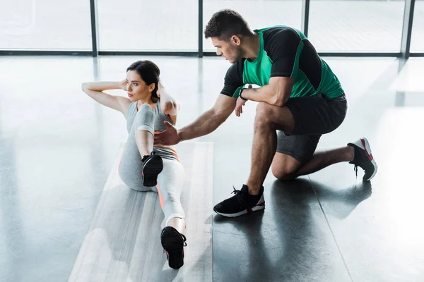 Sportswoman doing crunches and sportsman helping her in sports center — Stock Photo