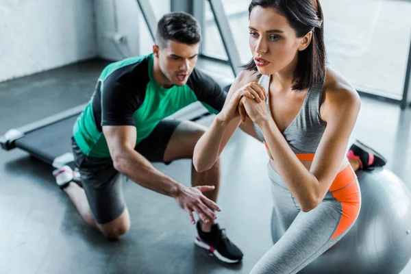 Sportswoman doing lunges on fitness ball and sportsman help her — Stock Photo