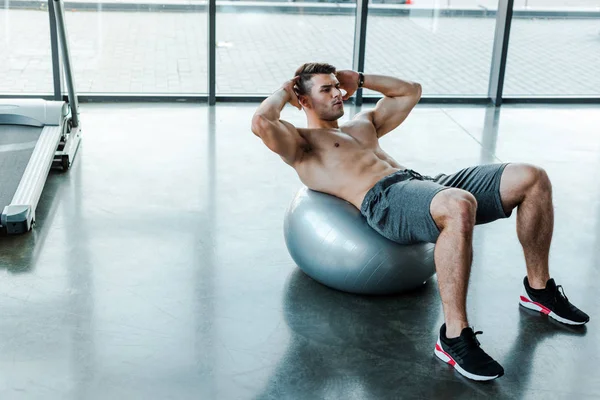 Handsome sportsman doing crunches on fitness ball in sports center — Stock Photo