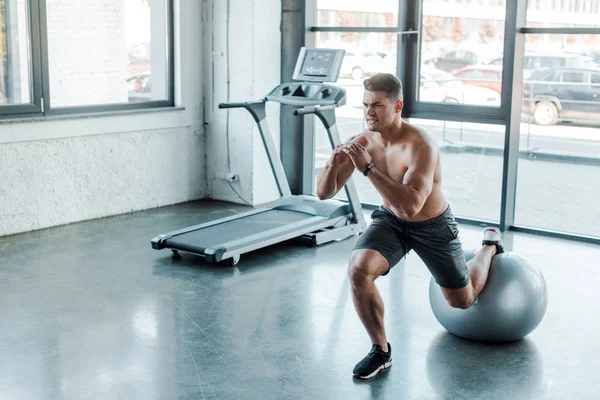 Desportista bonito fazendo lunges na bola de fitness no centro de esportes — Fotografia de Stock