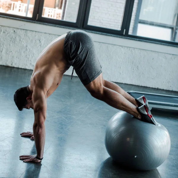 Desportista bonito trabalhando para fora na bola de fitness no centro de esportes — Fotografia de Stock