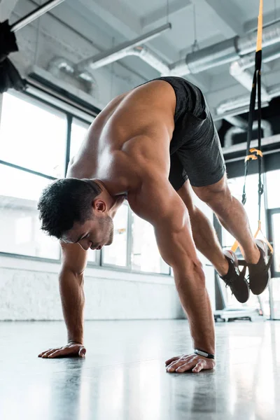 Handsome sportsman working out on suspension trainer in sports center — Stock Photo