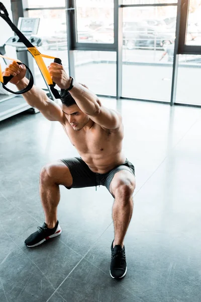 Handsome sportsman working out on suspension trainer in sports center — Stock Photo