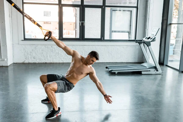 Schöner Sportler, der im Sportzentrum auf einem Aufhängungstrainer trainiert — Stockfoto