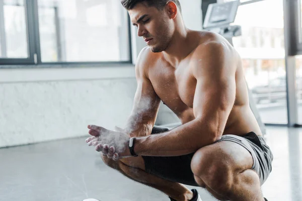 Handsome sportsman clapping hands with talc powder in sports center — Stock Photo