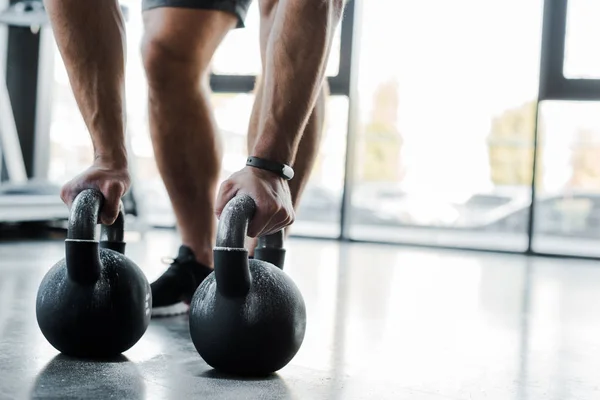 Cropped view of sportsman working out with weights in sports center — Stock Photo
