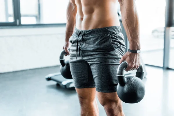 Cropped view of sportsman working out with weights in sports center — Stock Photo
