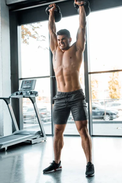 Deportista guapo haciendo ejercicio con pesas en el centro deportivo - foto de stock