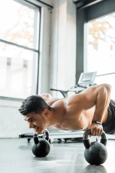 Handsome sportsman doing push ups on weights in sports center — Stock Photo