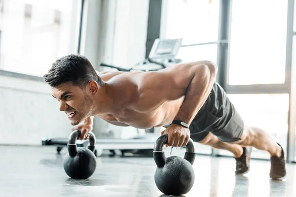 Handsome sportsman doing push ups on weights in sports center — Stock Photo