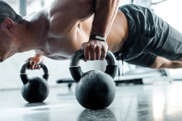 Cropped view of sportsman doing push ups on weights in sports center — Stock Photo