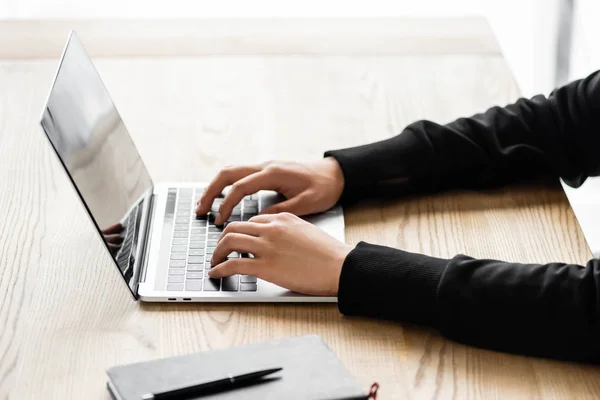 Vista cortada de hacker sentado à mesa e usando laptop — Fotografia de Stock