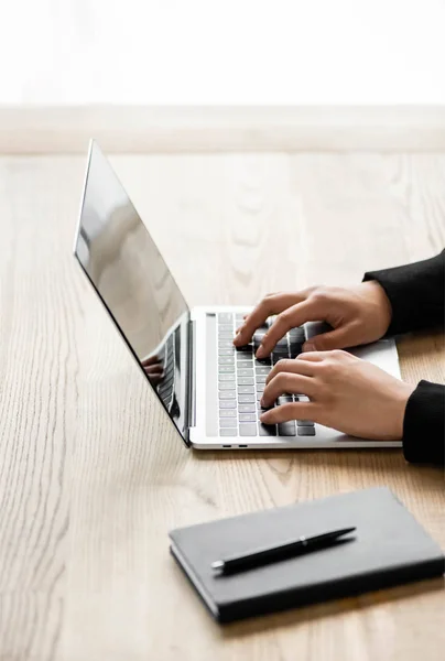 Cropped view of hacker sitting at table and using laptop — Stock Photo
