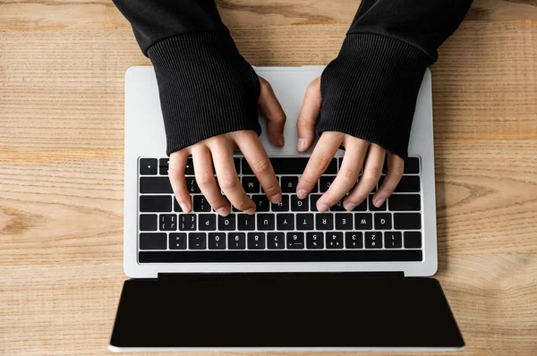 Vista recortada de hacker sentado en la mesa y el uso de ordenador portátil - foto de stock