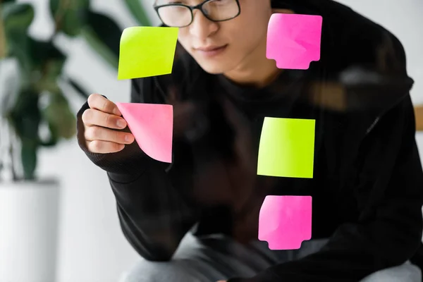 Asian seo manager in glasses taking sticky note from glass — Stock Photo