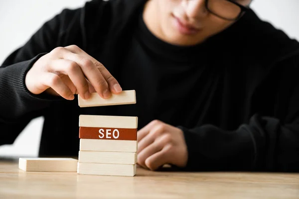 Vista ritagliata di seo manager che gioca con rettangoli di legno con scritte seo — Foto stock