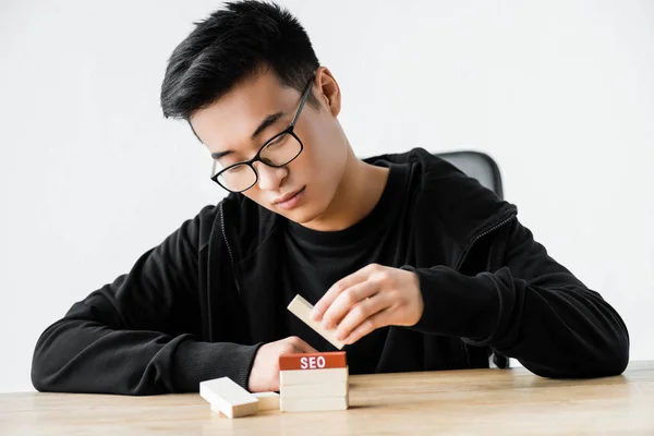 Asian seo manager playing with wooden rectangles with lettering seo — Stock Photo