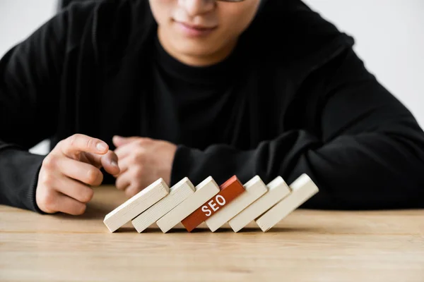 Vista ritagliata di seo manager che punta con il dito ai rettangoli di legno con lettering seo — Foto stock