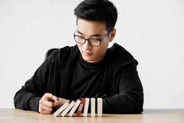 Asian seo manager playing with wooden rectangles with lettering seo — Stock Photo