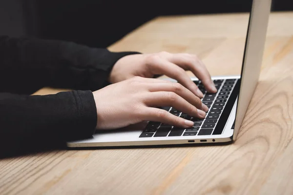 Vista cortada de hacker usando laptop e sentado à mesa — Fotografia de Stock