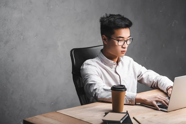 Asiatische seo manager sitzen am tisch und mit laptop — Stockfoto