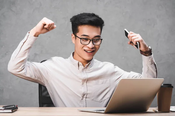 Lächelnder asiatischer SEO-Manager zeigt Ja-Geste und schaut auf Laptop — Stockfoto